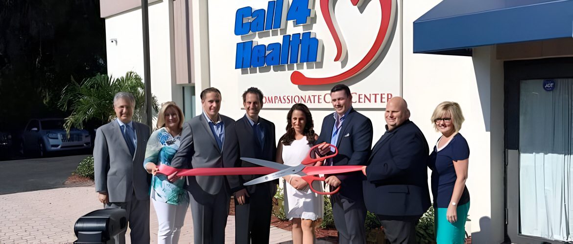 Group of people cutting ribbon at Call 4 Health Center grand opening.