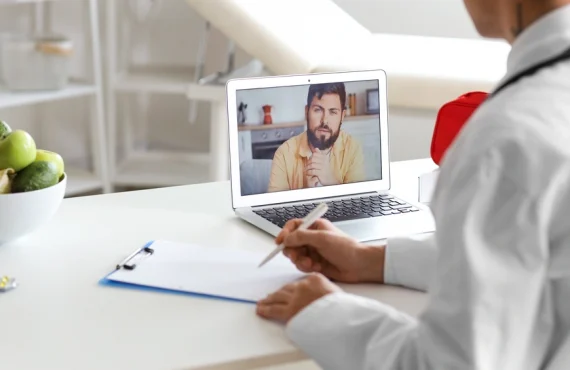 A doctor video chats with a patient using a laptop.