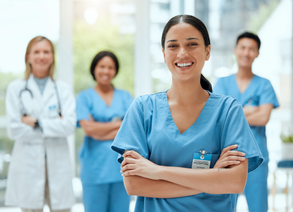 Portrait, medical and a woman nurse arms crossed, standing with her team in the hospital for healthcare. Leadership, medicine and teamwork with a female health professional in a clinic for treatment