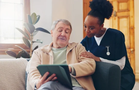 A senior man and his caregiver using a tablet to communicate and stay connected.