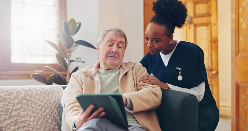 A senior man and his caregiver using a tablet to communicate and stay connected.